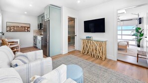 Una sala de estar moderna con un sofá, un televisor y una zona de cocina.