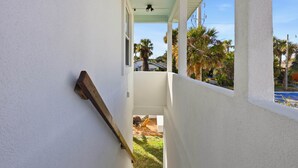 Una stretta scala conduce a un balcone con vista su palme e cielo azzurro.