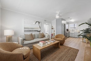 A modern living room with a sofa, armchairs, a coffee table, and a painting on the wall.