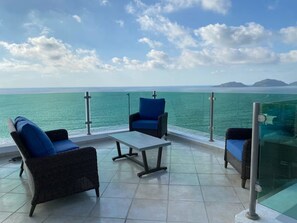 A terrace with wicker furniture and a glass balustrade overlooking the sea. - Vista Hermosa 56  (Mazatlán)