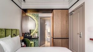 A hotel room with a bed, a green chair, a desk with a lamp, and a bathroom visible through an open door. - Hotel Santa Maria Maggiore (Rome)