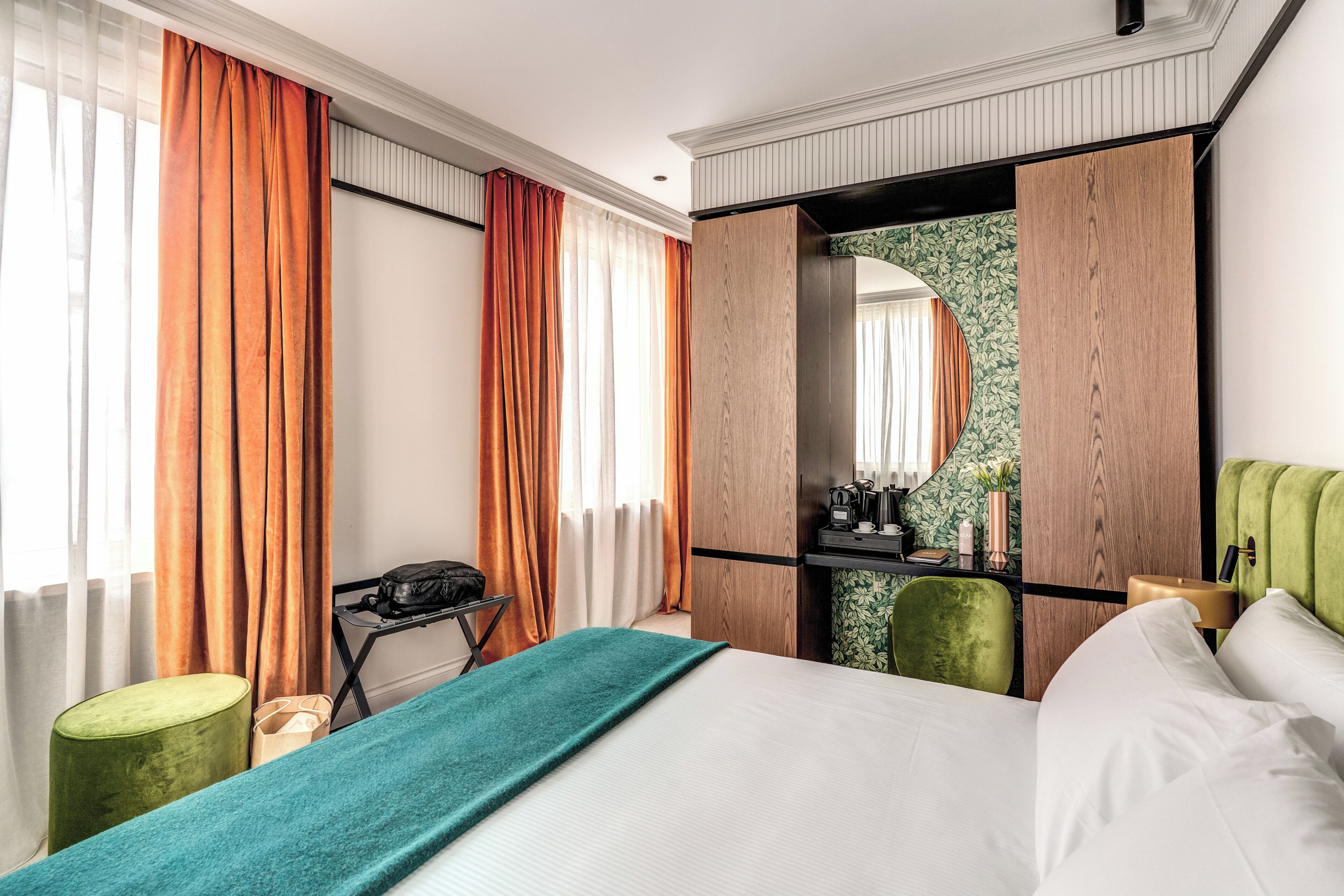 A hotel room with a bed, a desk, a chair, and a wardrobe.