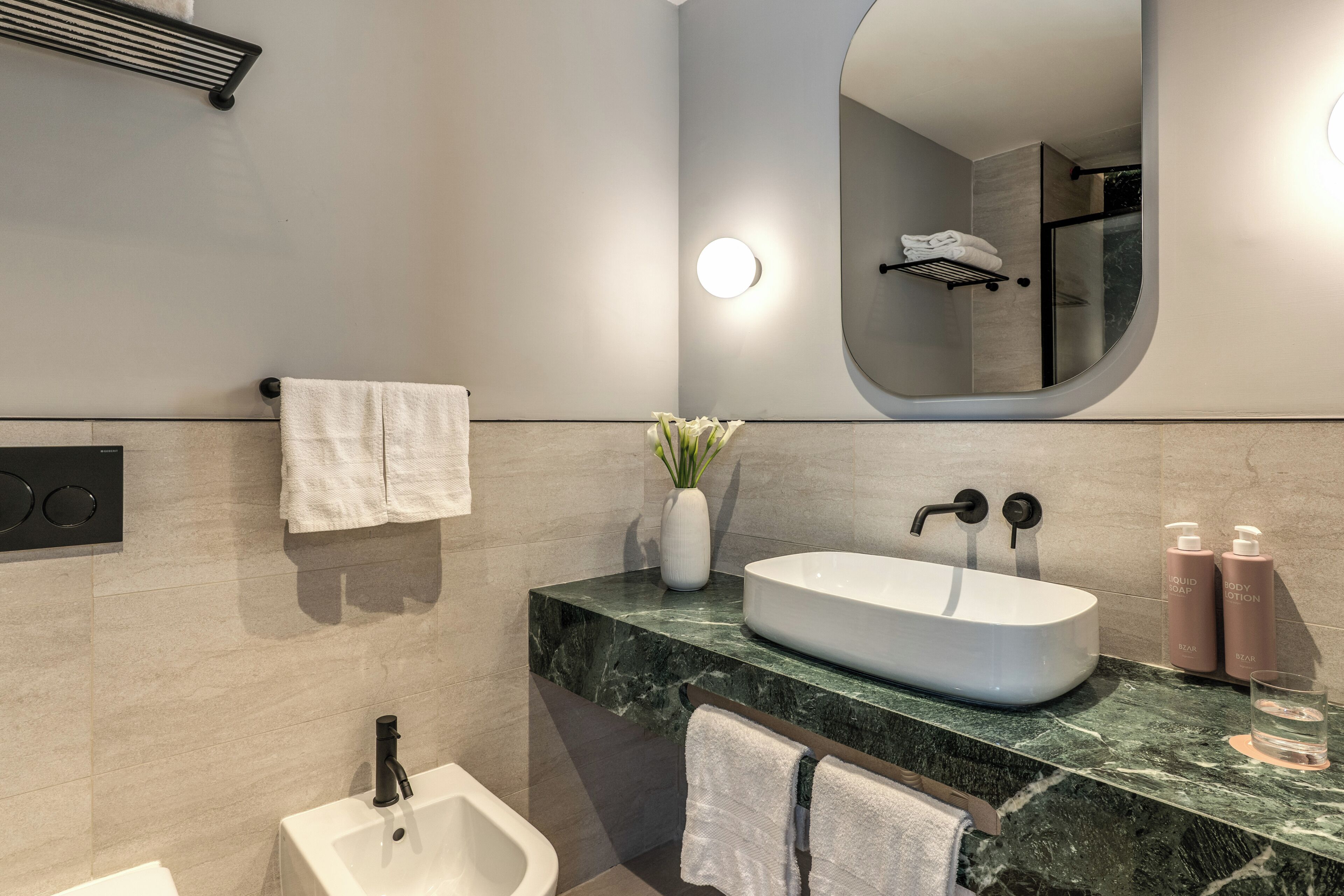 Une salle de bain moderne avec un lavabo blanc, un bidet, un miroir et un porte-serviettes.