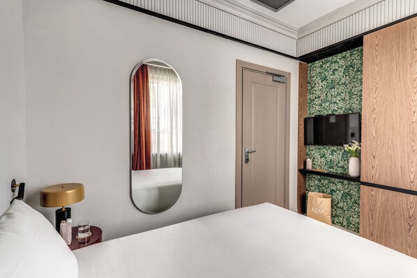A hotel room with a bed, a bedside table with a lamp, a mirror, a wardrobe, a TV, and a shelf with a vase. - Hotel Santa Maria Maggiore (Rome)