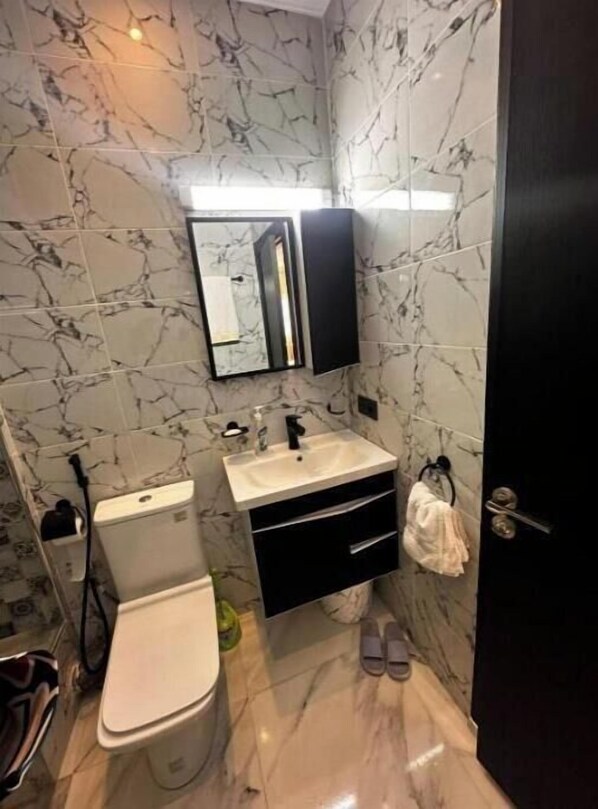 Een kleine badkamer met toilet, wastafel en spiegel.