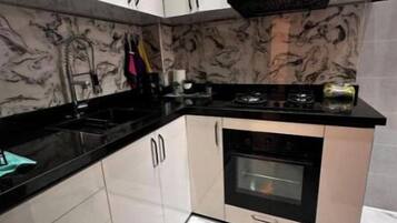 Eine kompakte Küche mit weißen Schränken, einer schwarzen Arbeitsplatte und einem eingebauten Backofen.