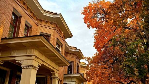 A two-story brick house with a porch, a visible number "412", and a tree with autumn leaves in the background.