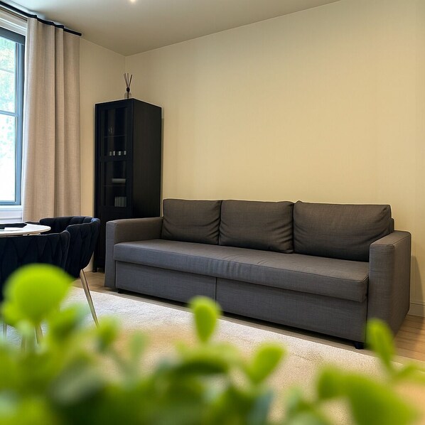 A modern living room with a grey sofa, a black cabinet, and a small table. - 3 KING BEDS • Free parking • Steps from Everything (Pittsburgh)
