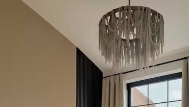 En pænt redt seng med sammenrullet håndklæder, et natbord med en ringlampe, og et stort vindue med udsigt til bygninger.