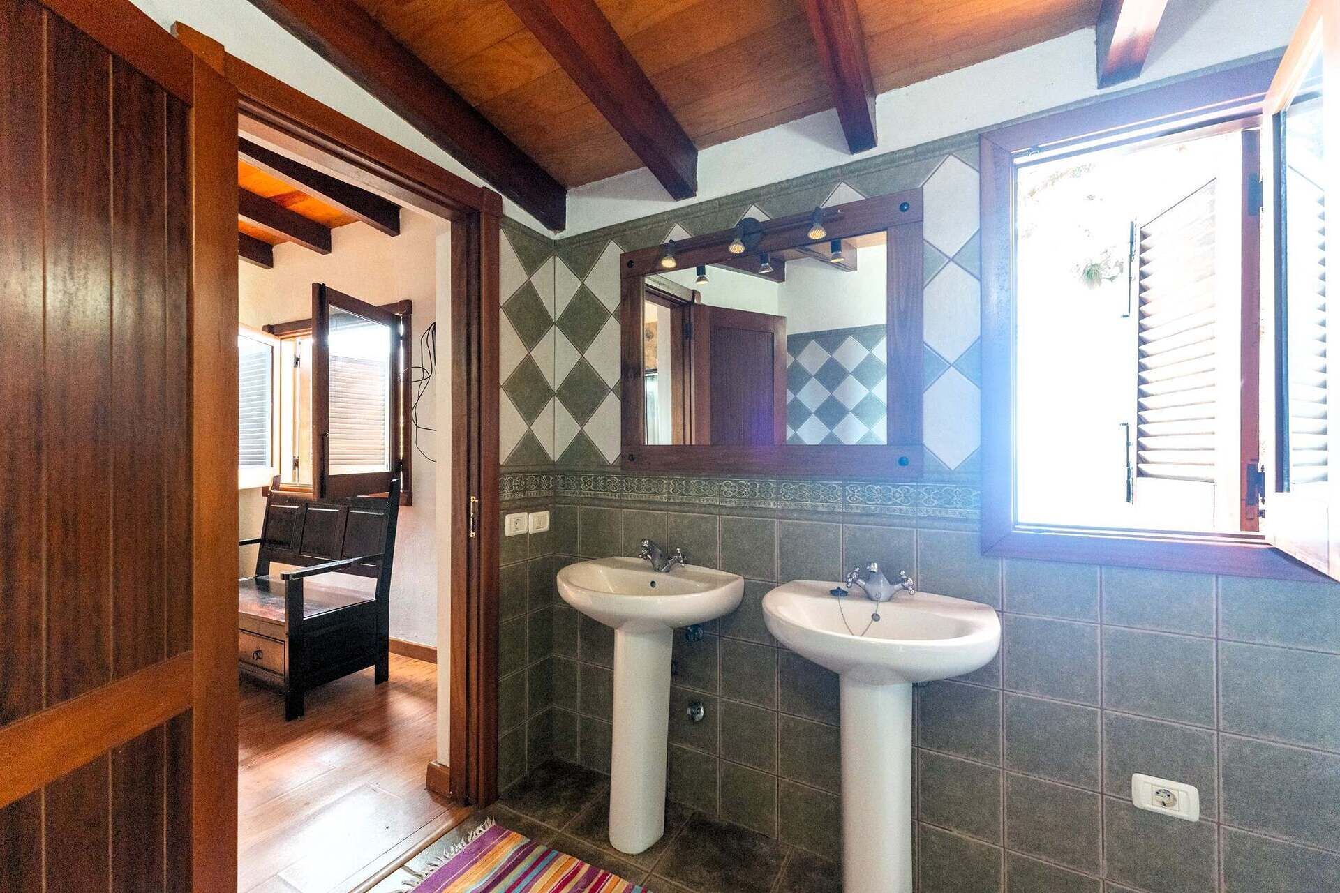 A bathroom with two sinks, a wooden ceiling, and a mirror.