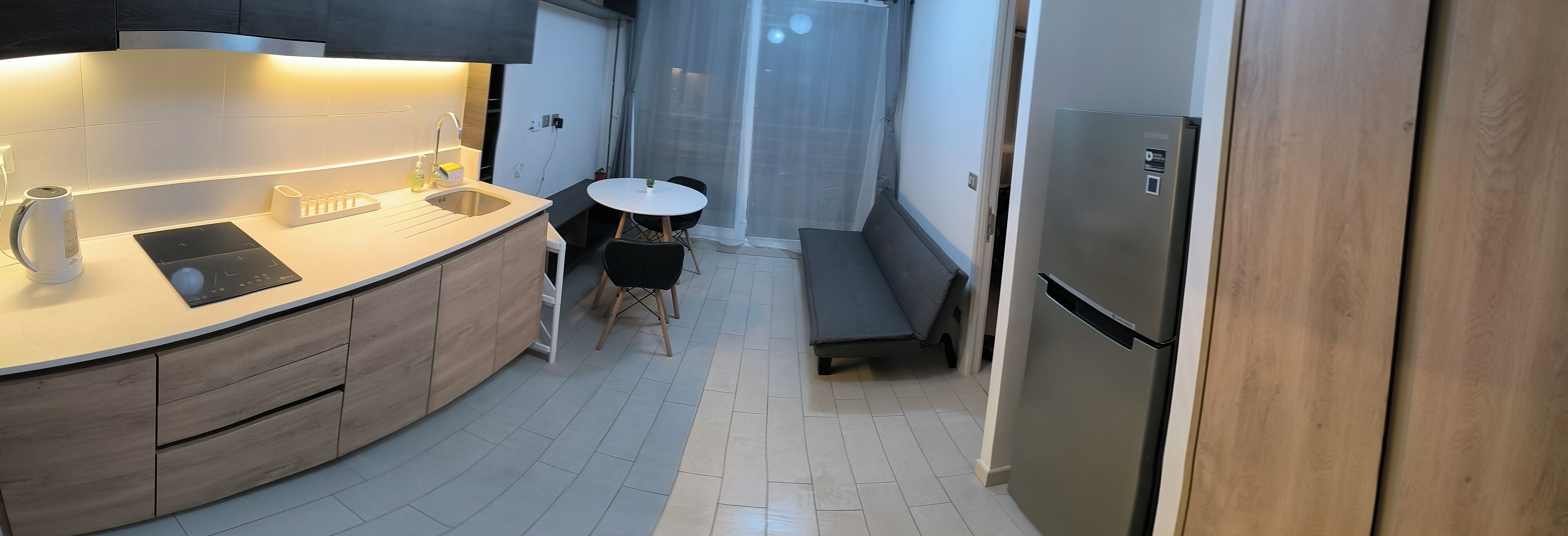A compact kitchen with a built-in sink, a small dining table, and a refrigerator.