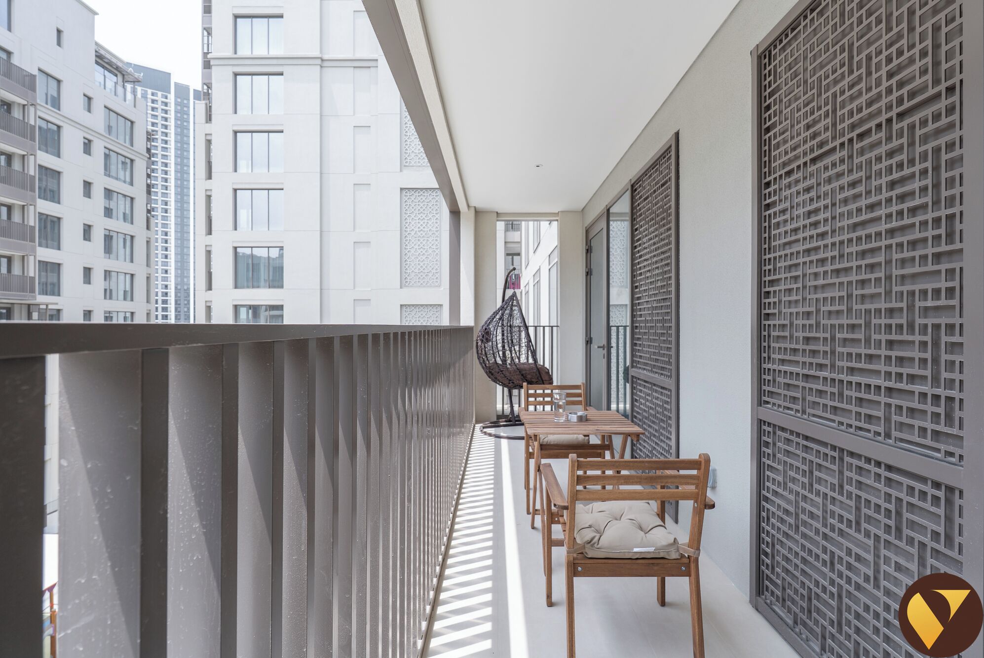Ein Balkon mit Blick auf angrenzende Gebäude, einem Hängestuhl und einem Tisch mit Stühlen.