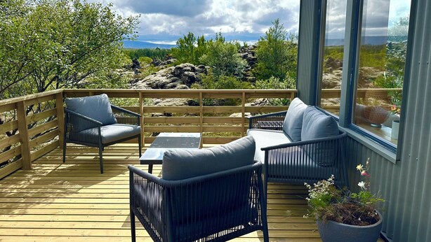 A wooden deck with outdoor furniture, a potted plant, and a view of a rocky landscape.
