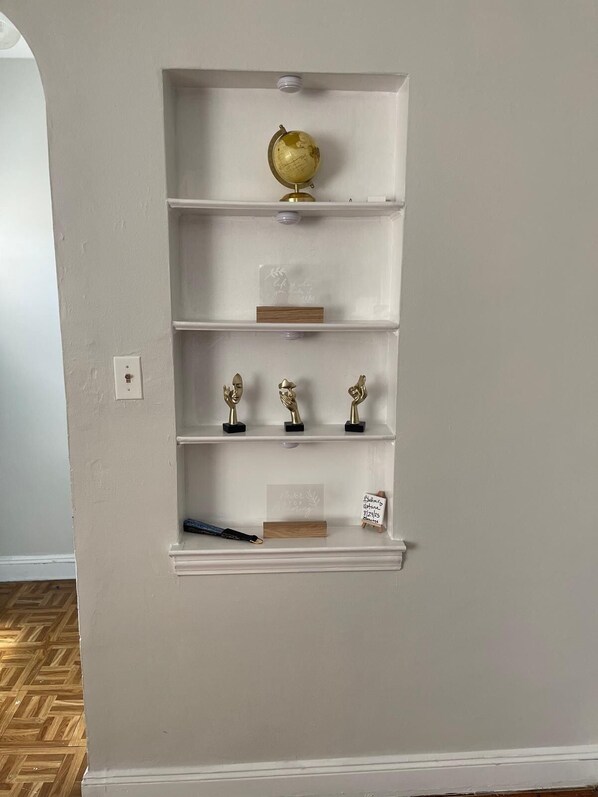 Una estantería blanca con un globo terráqueo, trofeos y una pequeña placa de madera.