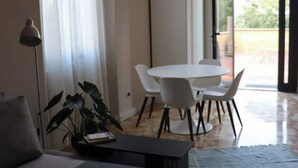 A modern dining area with a round table and white chairs, a potted plant, and a lamp. - Sonnino Terrace (Pisa)