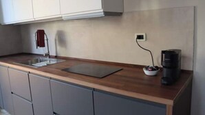 A modern kitchen with a wooden countertop, a built-in sink, and a coffee maker. - Sonnino Terrace (Pisa)