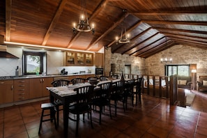Una cocina amplia con vigas de madera, un comedor con sillas y una pared de piedra.