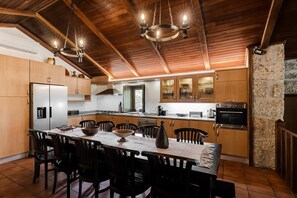 Una cocina con armarios de madera, una mesa de comedor con sillas y una araña.