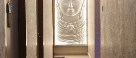 Un corridoio con un muro centrale che ospita una statua di Buddha.