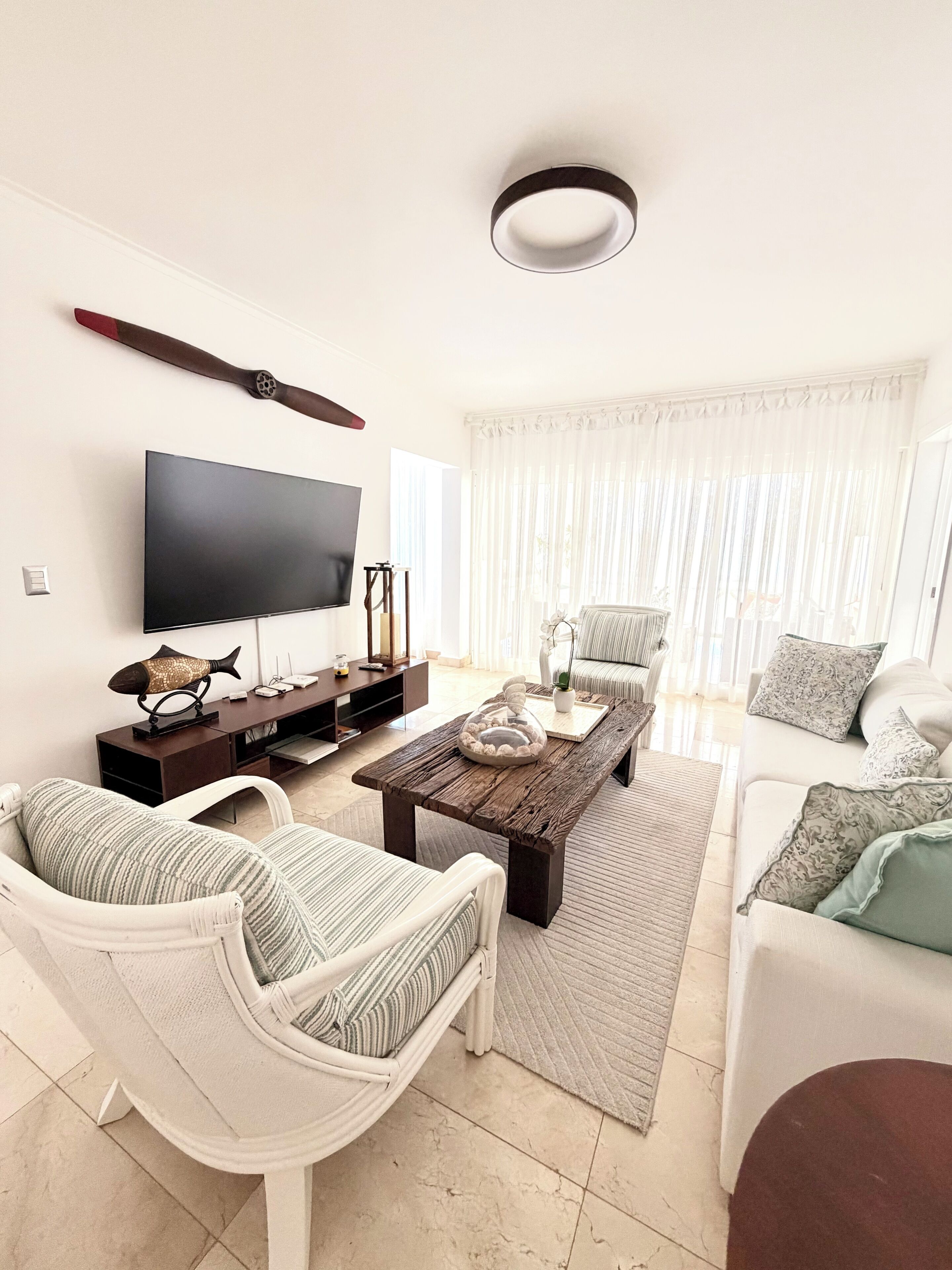 A modern living room with a flat-screen TV, a wooden coffee table, and a white sofa.