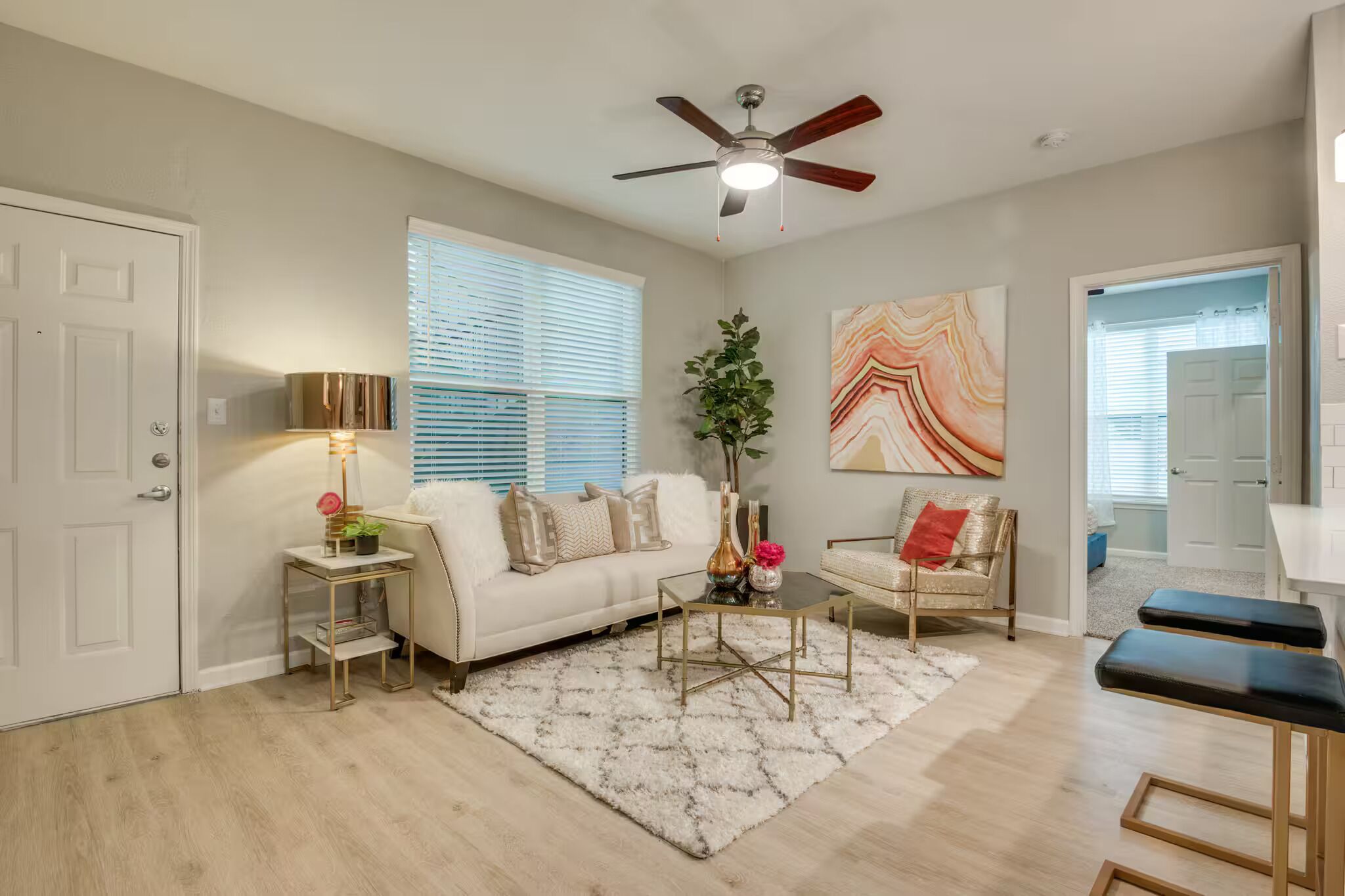 A living room with a white sofa, a coffee table, a side table with a lamp, and a ceiling fan.