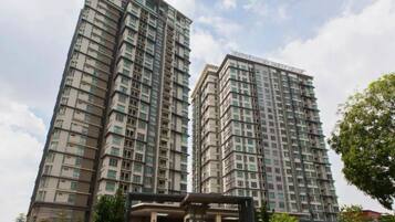 A high-rise residential building with multiple floors, a covered entrance, and a landscaped area in front.