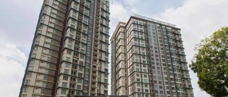 A high-rise residential building with multiple floors, a covered entrance, and a landscaped area in front.