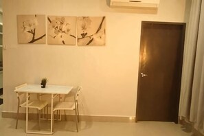 Um quarto com uma mesa de jantar e cadeiras, uma porta e três obras de arte penduradas na parede.