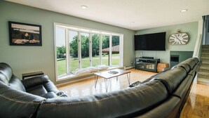 A living room with a large window, a sofa, a coffee table, a flat-screen TV, and a fireplace.