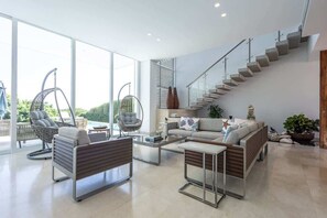 Un amplio salón con un sofá, dos sillones, una mesa de centro y una escalera.