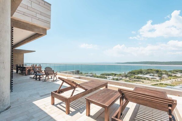 A rooftop terrace with outdoor furniture, a clear view of the sea, and a distant cityscape. - Isla Baru retreat with pool and gym (Cartagena de Indias)