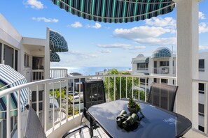 A balcony with a table, chairs, and a pair of binoculars.