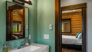 A bathroom with a sink, mirror, and wooden walls. - Cabin Getaway in Pray, MT (Pray)