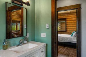 A bathroom with a sink, mirror, and wooden walls.