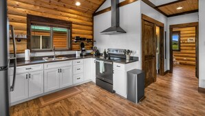A modern kitchen with wooden paneling, stainless steel appliances, and a large window. - Cabin Getaway in Pray, MT (Pray)
