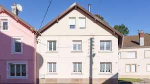 Un immeuble à plusieurs étages doté d’une façade symétrique, avec des fenêtres régulièrement espacées et une entrée centrale.