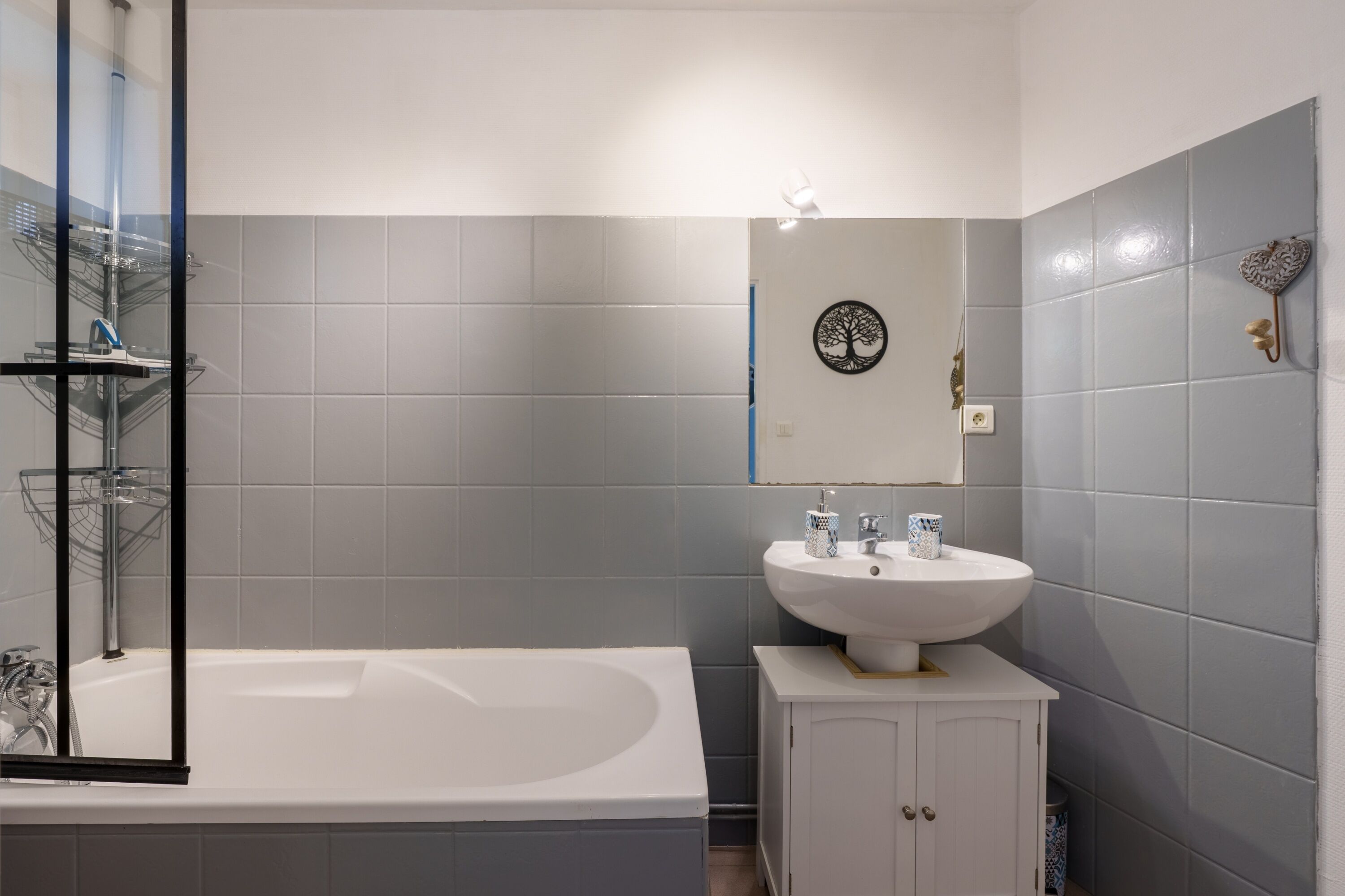 A modern bathroom with a bathtub, a white sink, and a mirror.