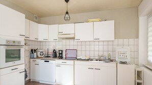 Une cuisine moderne avec des meubles blancs, un lave-vaisselle, une cuisinière et un réfrigérateur.