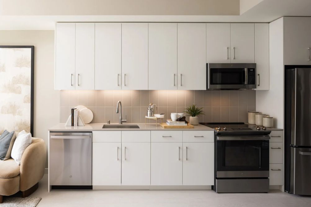 A modern kitchen with white cabinets, a built-in microwave, a stove, and a dishwasher.