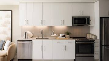 A modern kitchen with white cabinets, a built-in microwave, a stove, and a dishwasher.