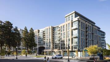 A multi-story building with a modern architectural design, featuring a mix of glass and concrete facades, and a central entrance with a covered area.
