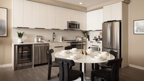 A modern kitchen with white cabinets, stainless steel appliances, and a round dining table with black chairs. - The Martin 2BR Retreat | Hot Tub & Outdoor Pool (Sunnyvale)