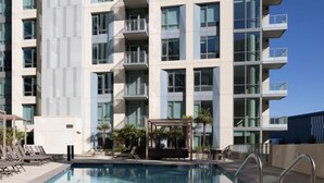 A modern hotel with a swimming pool, multiple balconies, and a covered outdoor seating area. - The Martin 2BR Retreat | Hot Tub & Outdoor Pool (Sunnyvale)