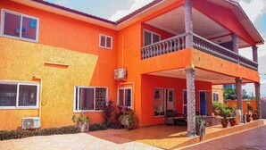 A two-story building with a balcony, large windows, and potted plants. - VIST One-Bedroom Apartment with Pool View (Accra)