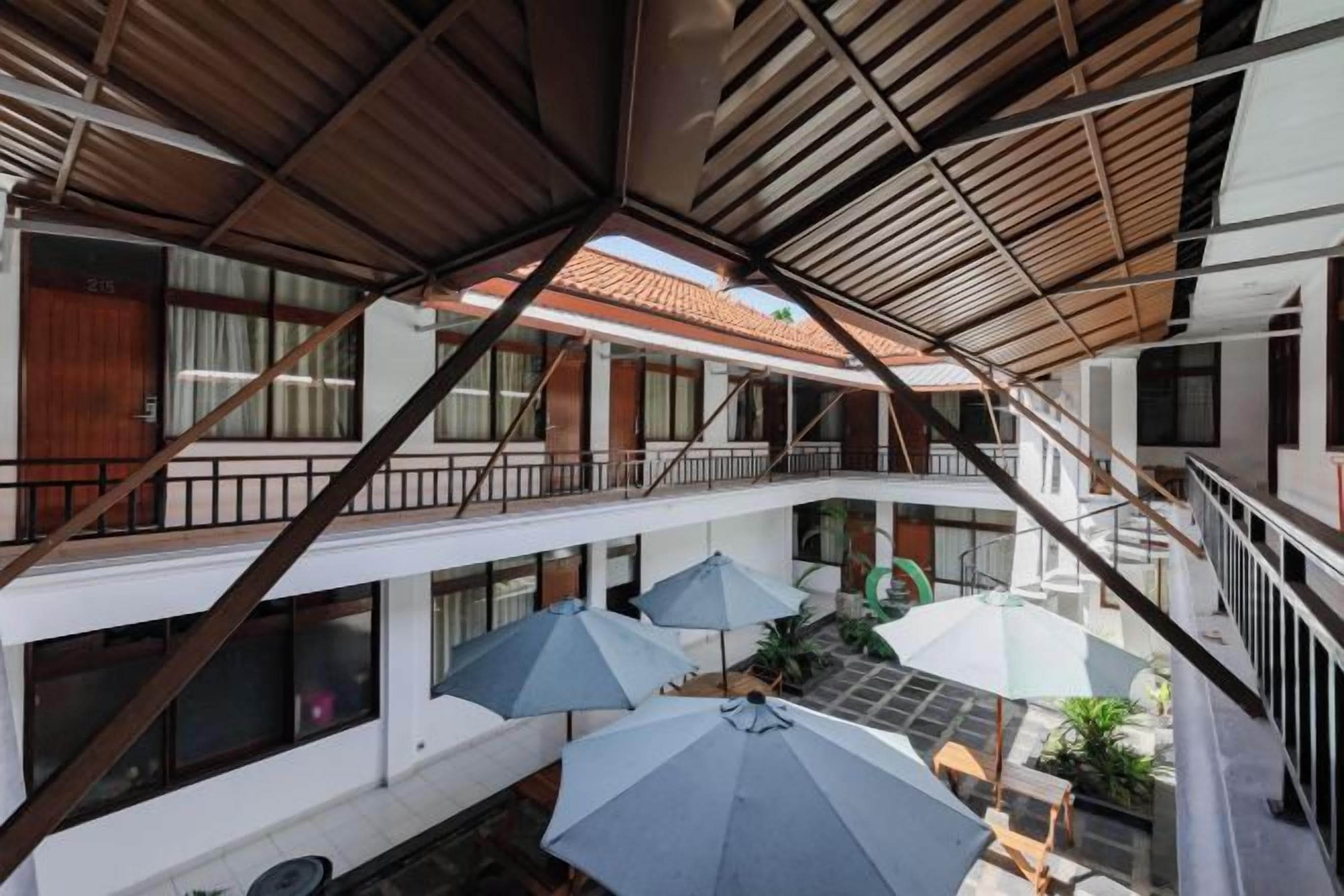 A multi-level hotel interior with balconies, outdoor seating, and a central atrium.