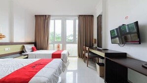A hotel room with two beds, a desk, a TV, and a window with curtains.