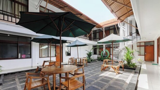 A courtyard with wooden furniture, umbrellas, and potted plants.