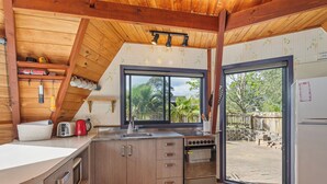A kitchen with wooden cabinets, a sink, a stove, and a window overlooking a garden.