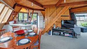 A cozy, wooden interior with a dining area, kitchen, and entertainment setup.