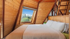 A bedroom with a wooden ceiling and a large window.